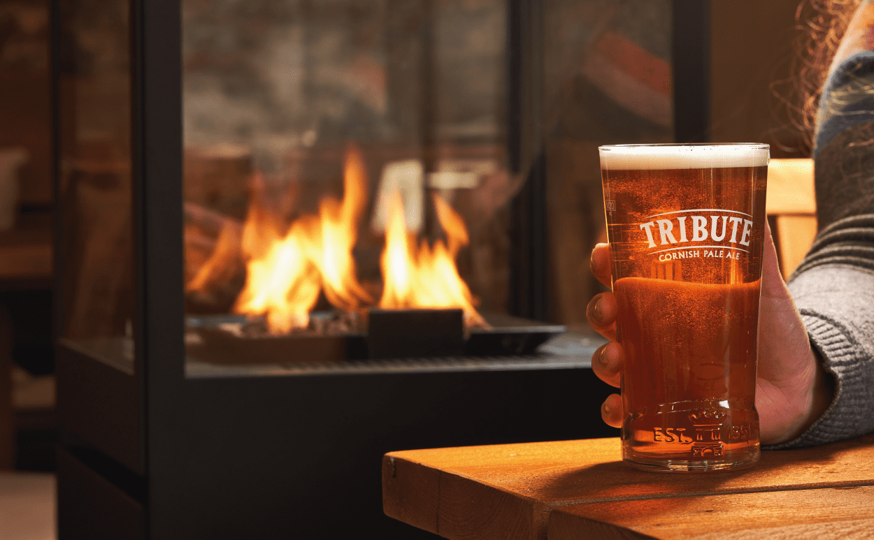 Pint of Tribute beside fireplace