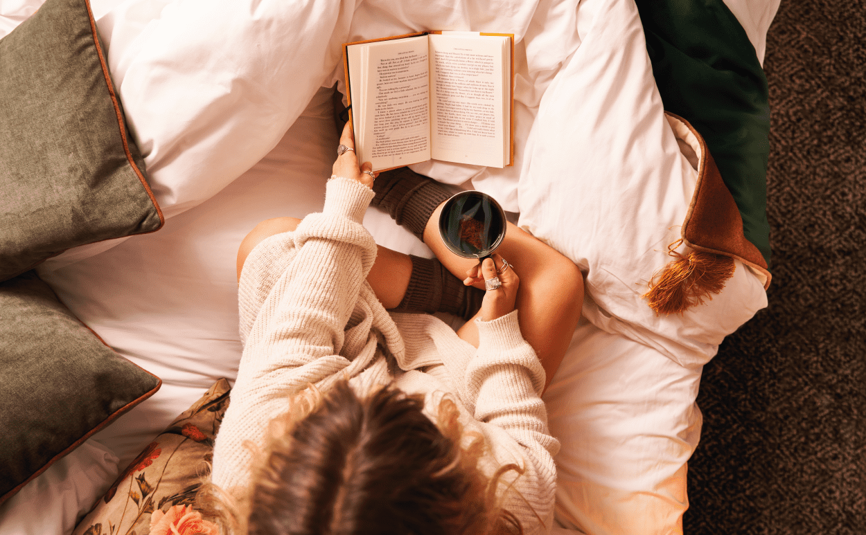 Woman reading in bed with tea